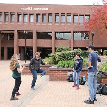 学生们在365bet体育亚洲官方入口主校区的比灵顿图书馆外玩曲棍球.