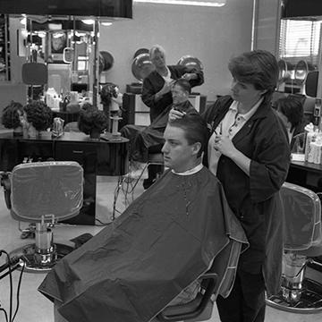 A cosmetology student cuts a man's hair.